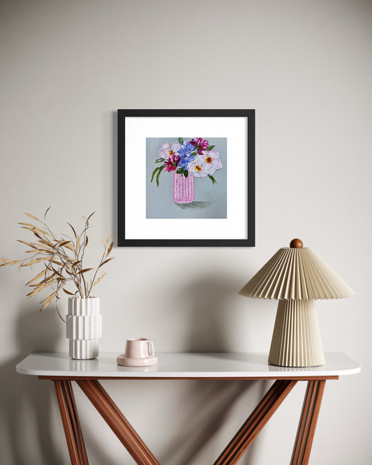 Mix and match floral painting displayed in a black frame above a wooden console